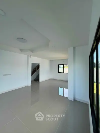 Spacious modern living room with large windows and glossy tiled floors