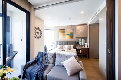 Elegant bedroom with plush bedding, modern furnishings, and a cozy sitting area leading to a well-appointed study space, bathed in natural light.