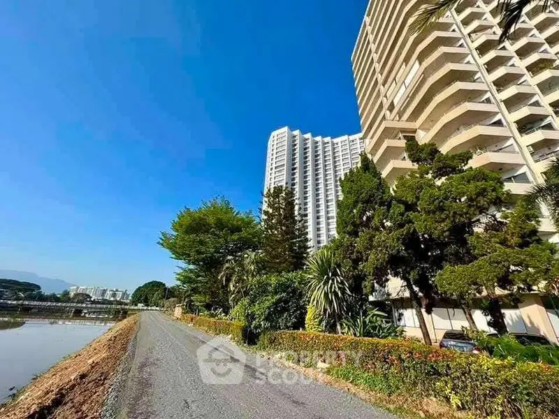 Stunning high-rise building with lush greenery and clear blue sky, perfect for modern living.
