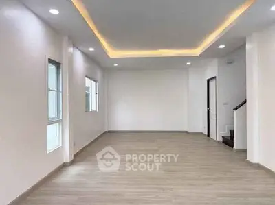 Spacious modern living room with recessed lighting and wooden flooring.