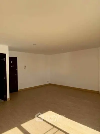 Spacious empty room with wooden flooring and ample natural light