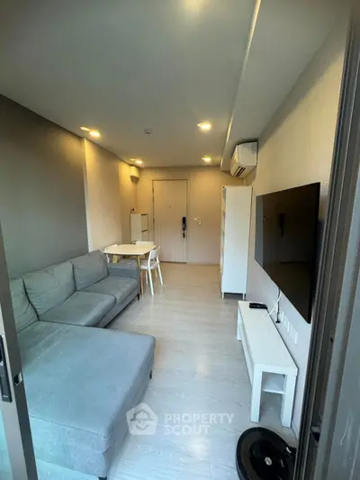 Modern living room with sleek furniture and wall-mounted TV in a cozy apartment.