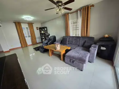Spacious living room with modern furniture and ceiling fan, perfect for relaxation.