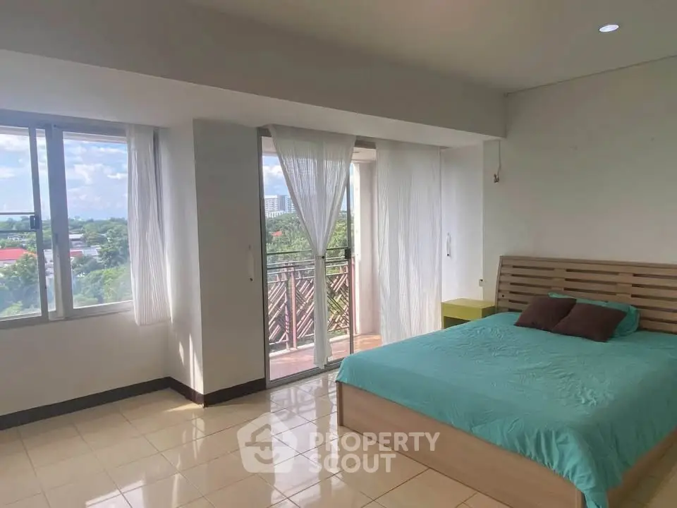 Spacious bedroom with large windows and balcony access, offering a serene view.
