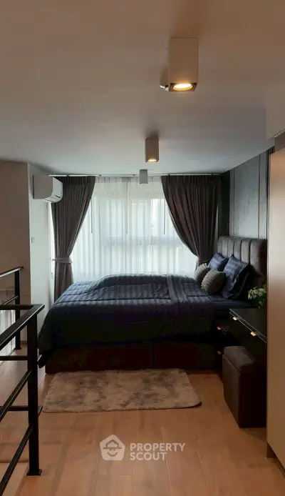 Modern bedroom with stylish decor and large window for natural light.