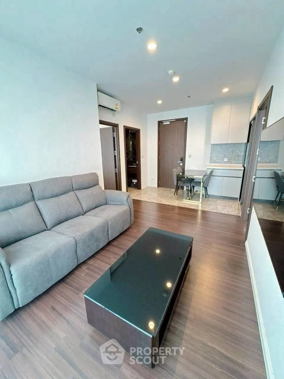 Modern living room with sleek furniture and open kitchen layout in a stylish apartment.