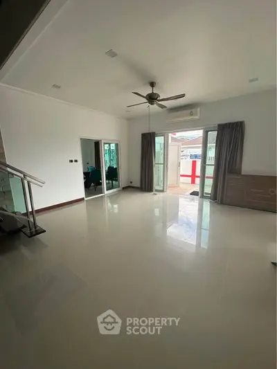 Spacious living room with ceiling fan and large windows for natural light