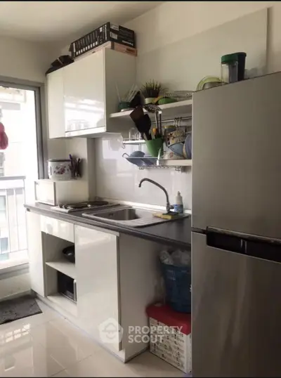 Modern kitchen with sleek cabinets and stainless steel fridge in a bright apartment.