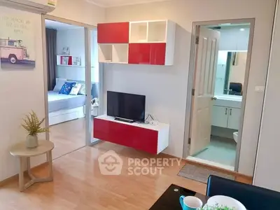 Modern apartment interior with open living room and bedroom view, featuring stylish red and white decor.