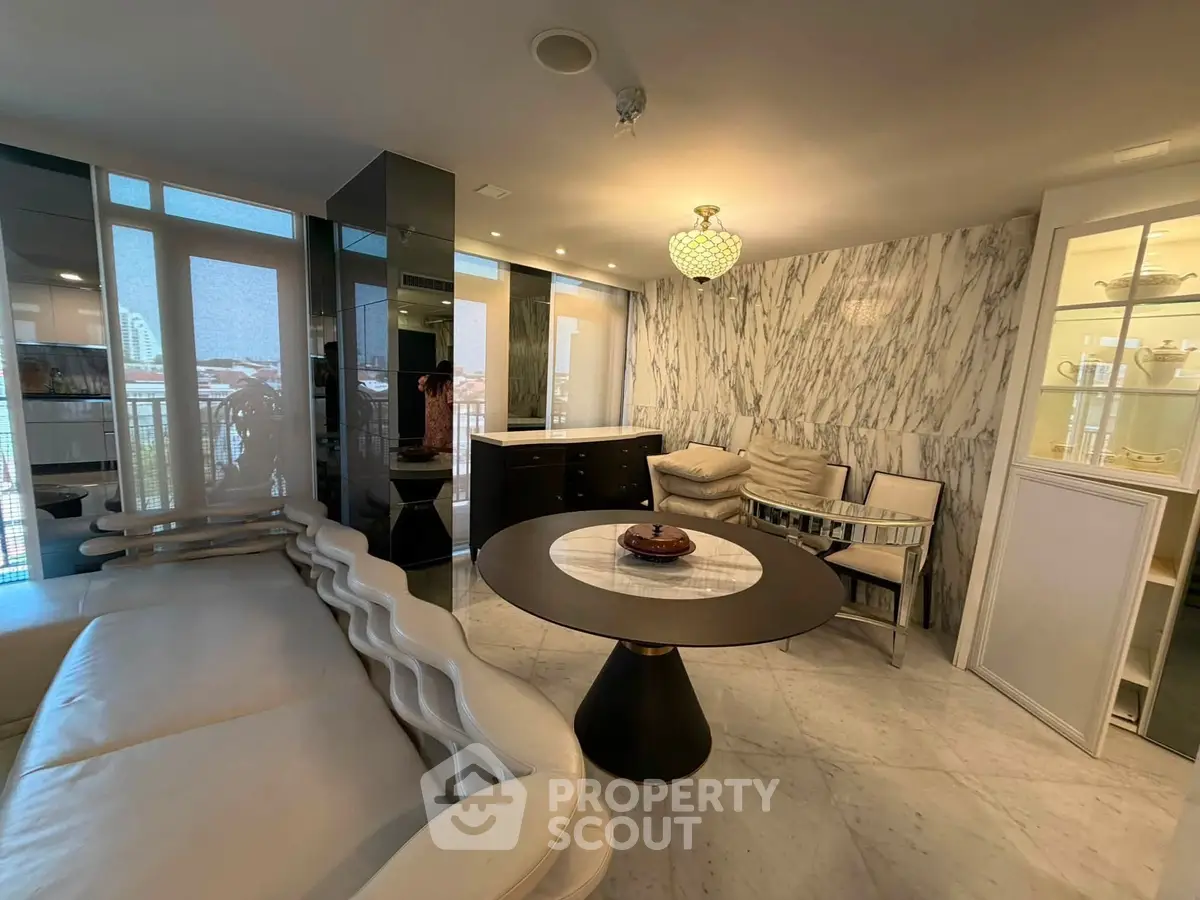 Luxurious living room with marble walls and modern furniture, featuring a round table and elegant lighting.