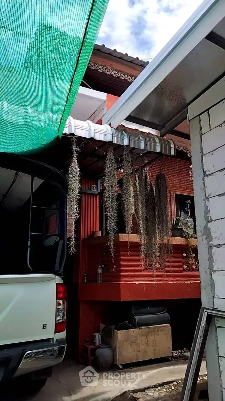 Charming rustic exterior with red brick and hanging plants, perfect for cozy living.