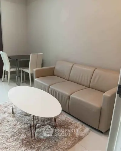 Modern living room with beige sofa, white coffee table, and dining area in stylish apartment.