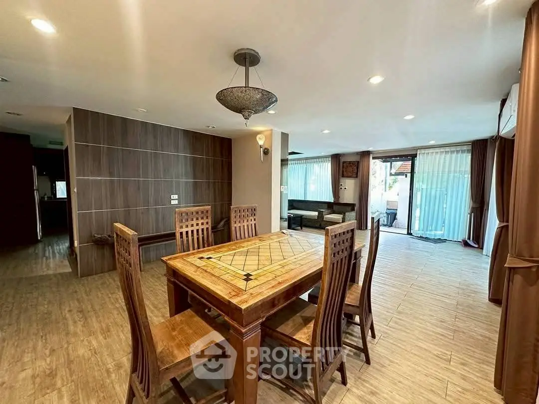 Spacious open-plan living and dining area with elegant wooden furniture and large windows.
