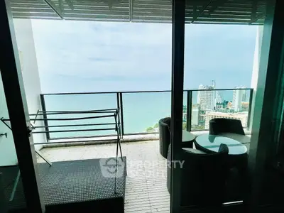 Stunning high-rise balcony with ocean view and outdoor seating area.