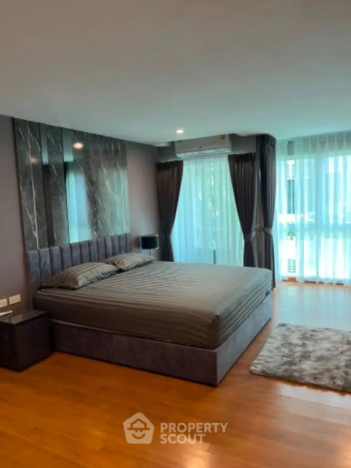 Spacious bedroom with modern decor and large windows offering natural light.
