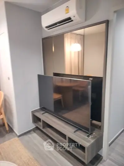 Modern living room with sleek TV setup and air conditioning unit, perfect for cozy entertainment.