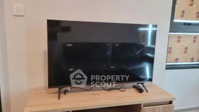 Modern living room with sleek TV on wooden stand, perfect for entertainment.