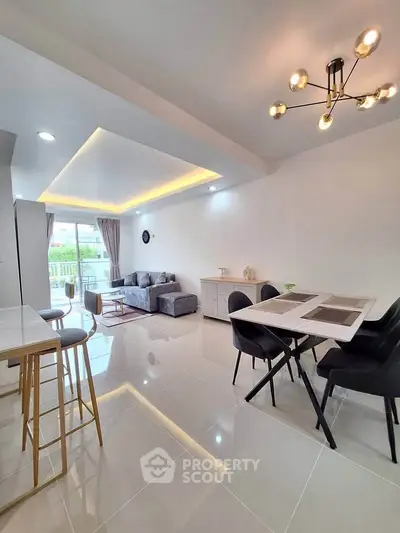 Modern open-plan living and dining area with stylish lighting and balcony view.