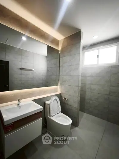 Modern bathroom with sleek fixtures and large mirror in a contemporary home.