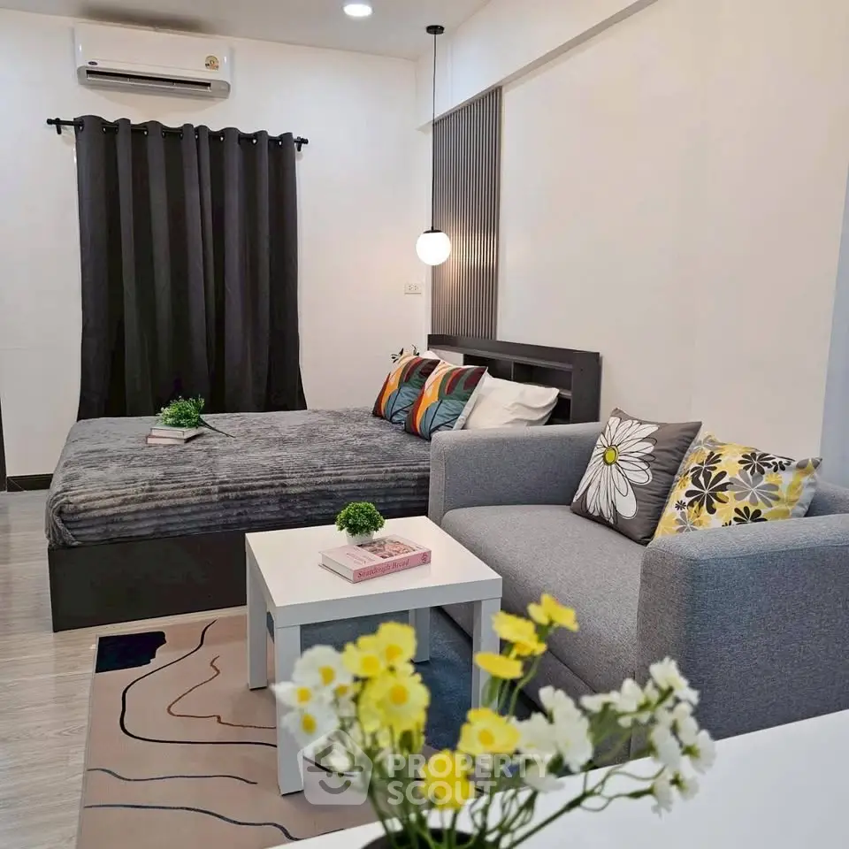 Modern studio apartment with cozy bed and stylish sofa in a well-lit room.