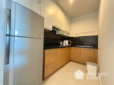 Modern kitchen with sleek cabinets and stainless steel fridge in a cozy apartment