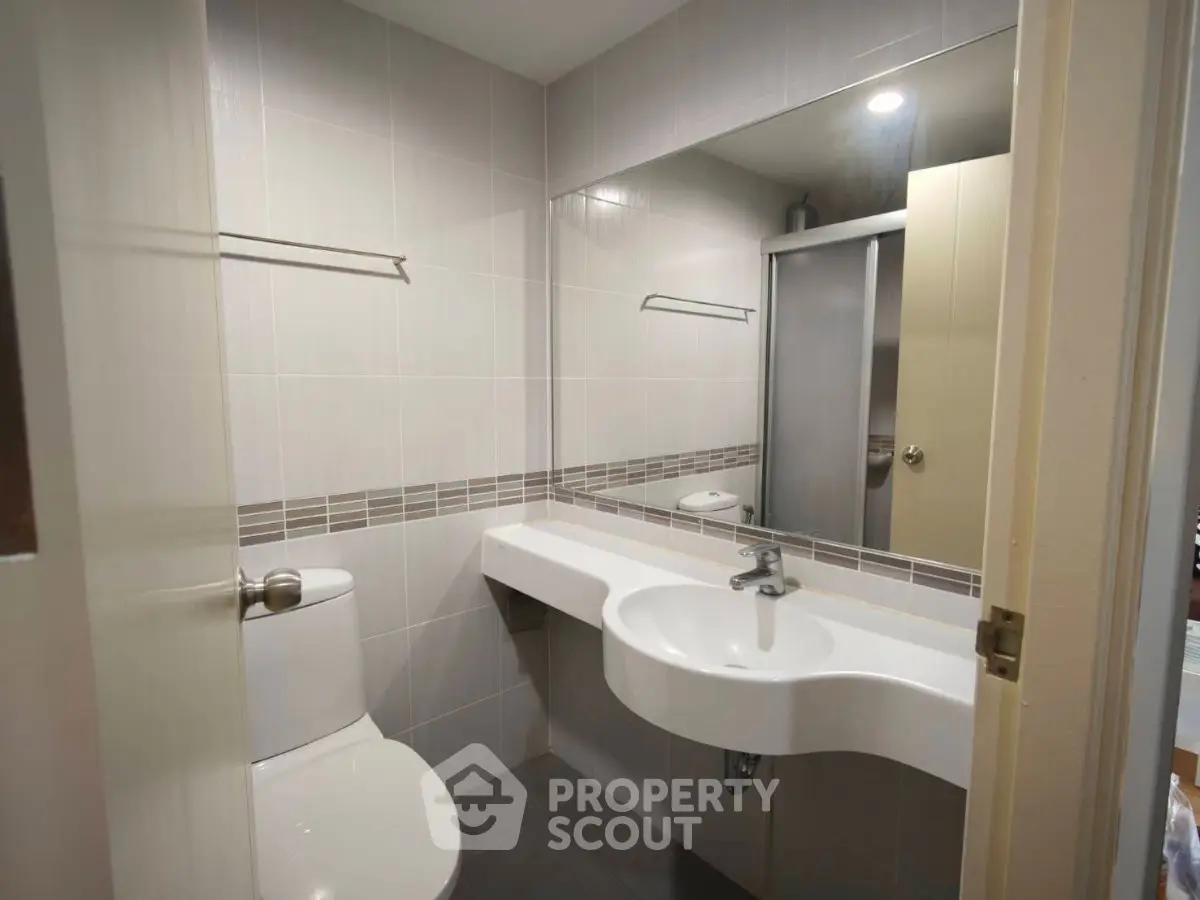 Modern bathroom with sleek fixtures and large mirror in a contemporary apartment.
