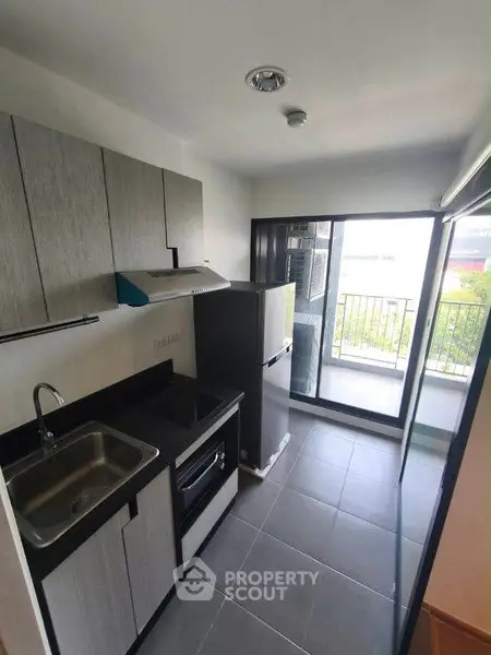 Modern kitchen with sleek cabinetry and balcony access in a stylish apartment.