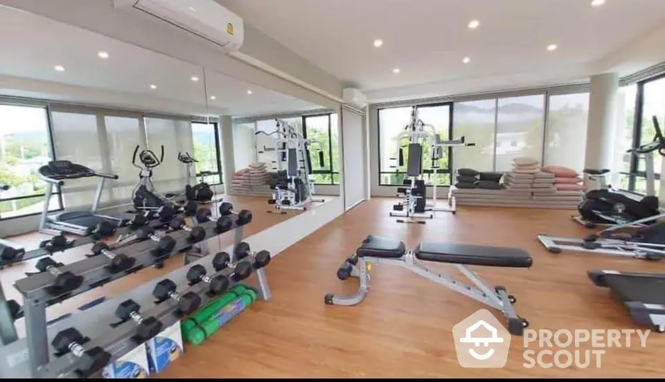 Modern gym with panoramic windows and fitness equipment in luxury apartment complex