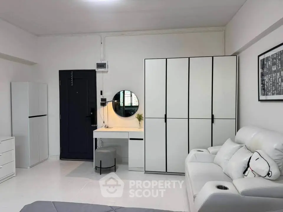 Modern minimalist bedroom with sleek white furniture and cozy seating area.