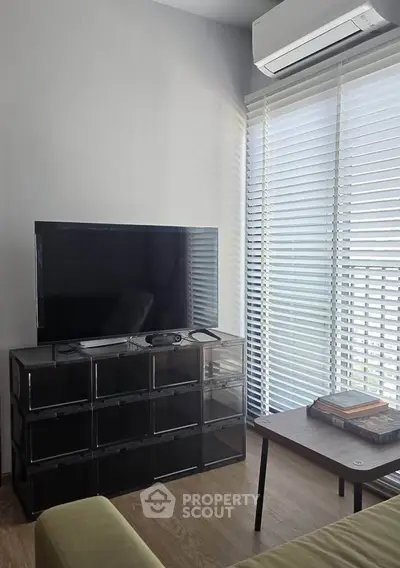 Modern living room with sleek TV setup and natural light from large windows.