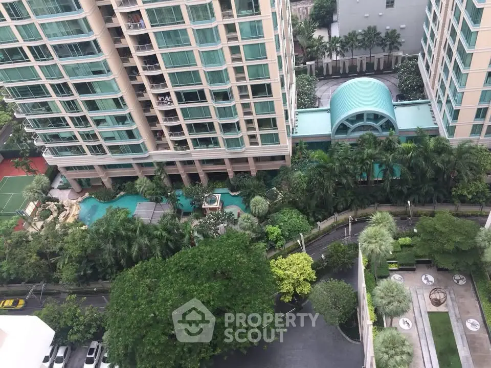 Aerial view of luxurious condominium with lush gardens and pool area, showcasing modern architecture and urban living.