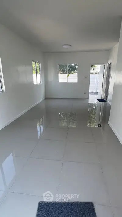 Spacious empty room with glossy tiled floors and large windows, perfect for customization.