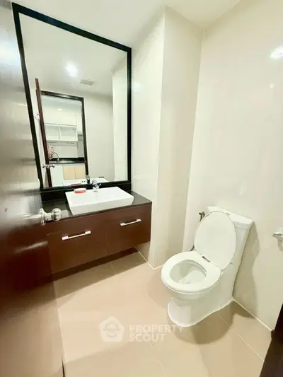 Modern bathroom with sleek fixtures and large mirror in a contemporary home.