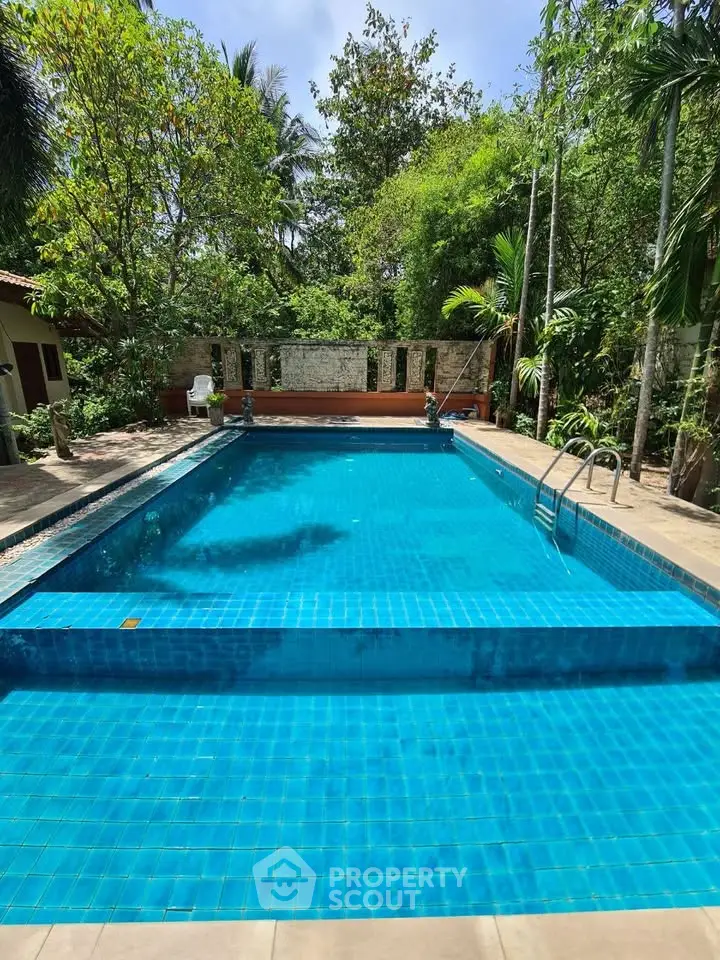 Stunning outdoor pool surrounded by lush greenery, perfect for relaxation and leisure.