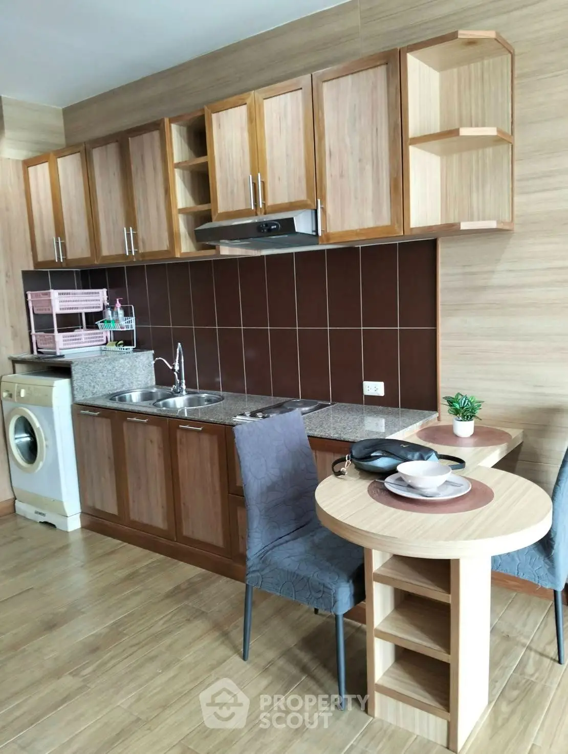 Modern kitchen with wooden cabinets, washing machine, and cozy dining area.