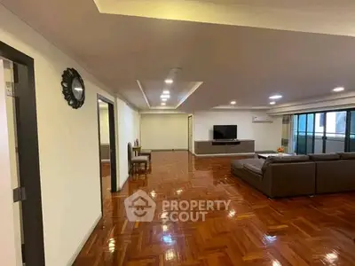 Spacious living room with polished wooden floors and modern furniture in a luxurious apartment.
