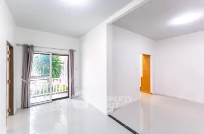 Spacious and bright living room with large window and garden view, perfect for modern living.