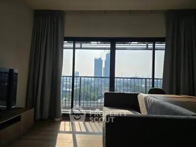 Modern living room with large windows offering a stunning city view, featuring a sleek sofa and entertainment unit.