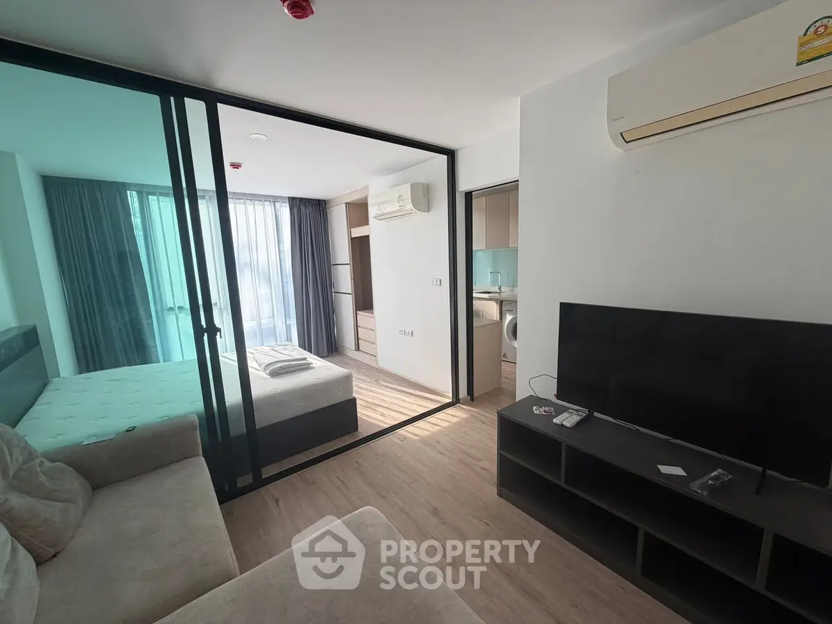 Modern apartment interior with open living room and bedroom layout, featuring sleek furniture and natural light.