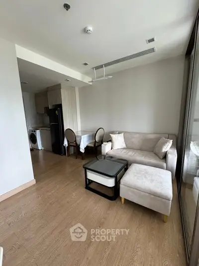 Modern living room with cozy sofa, dining area, and kitchen appliances in open layout.