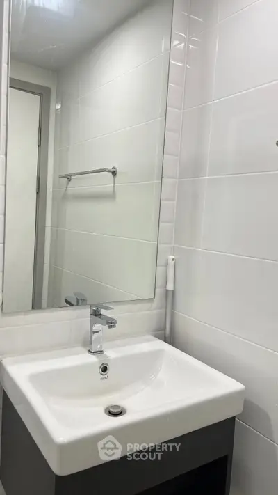 Modern bathroom with sleek white sink and large mirror in a contemporary apartment.