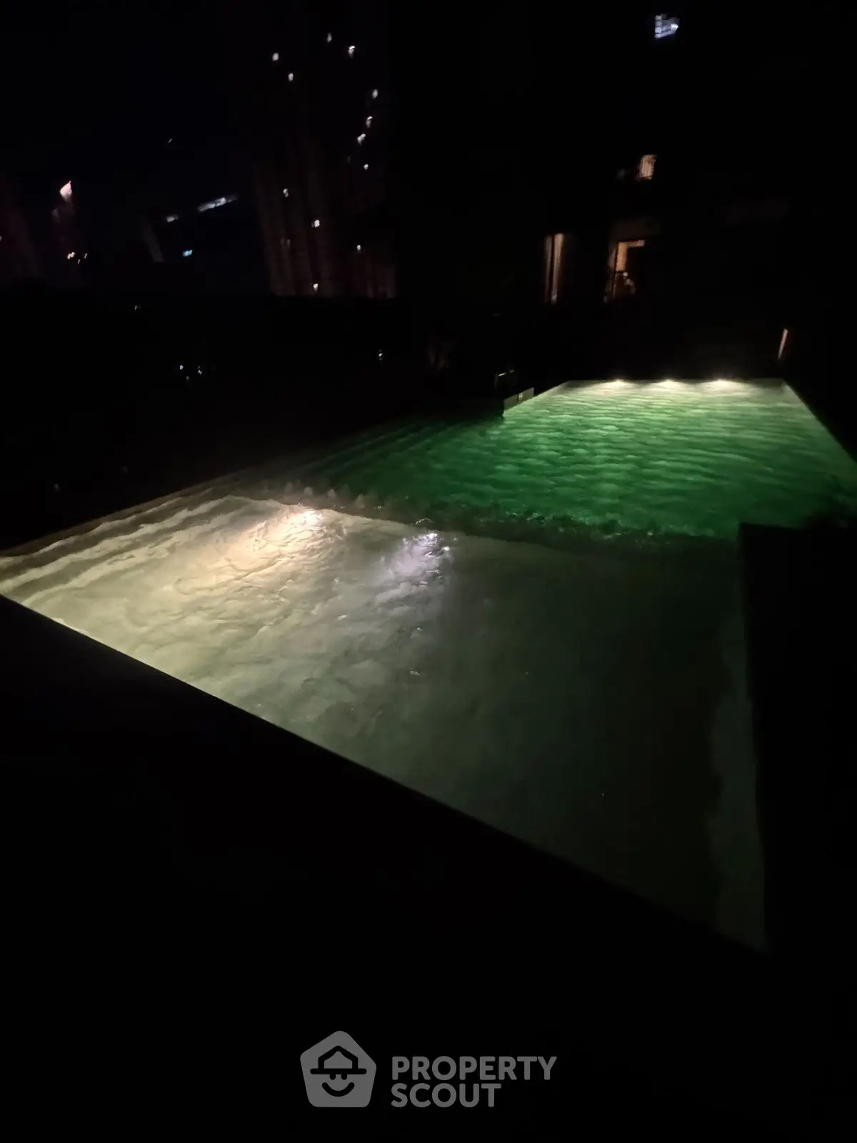 Luxurious night view of illuminated swimming pool in upscale residential complex.