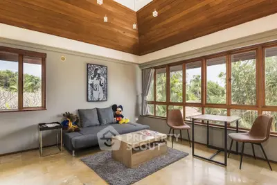 Spacious living room with large windows and modern decor, featuring a cozy sofa and wooden ceiling.