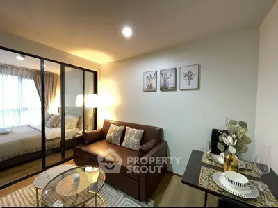 Modern living room with cozy sofa, elegant decor, and a view into a stylish bedroom through glass doors.