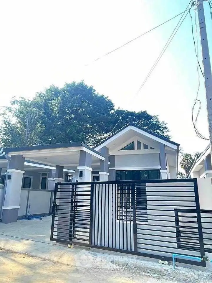 Modern single-story house with sleek metal gate and lush greenery