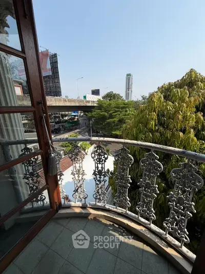 Charming balcony with ornate railing offering a scenic city view, perfect for relaxation and enjoying urban life.