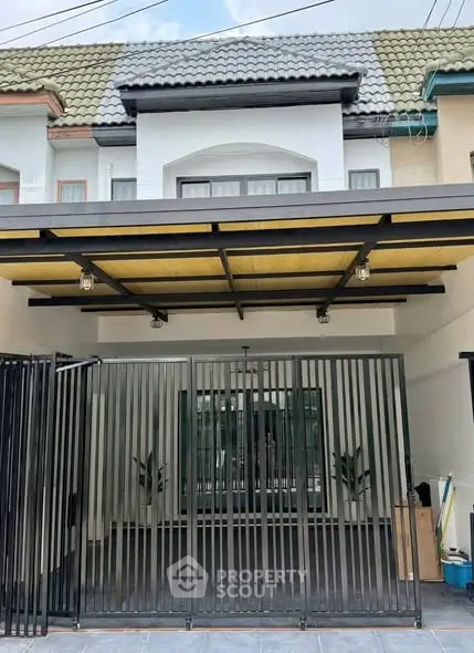 Charming townhouse exterior with gated entrance and modern roof design.