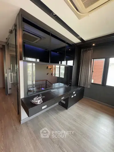 Modern living room with sleek black cabinetry and large windows offering natural light.