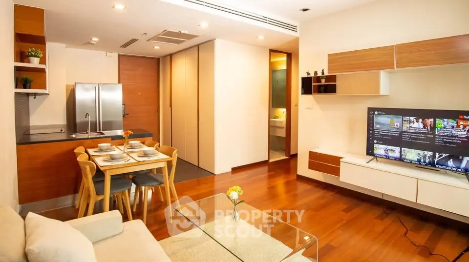 Modern open-plan living room with sleek kitchen and dining area, featuring wooden flooring and stylish decor.