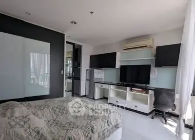 Modern bedroom with sleek furniture, TV, and air conditioning in a stylish apartment.